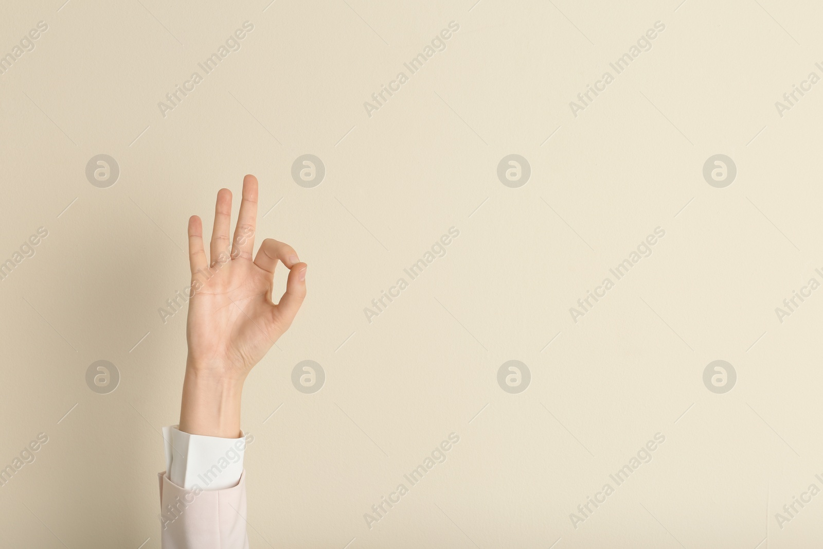 Photo of Young woman showing OK gesture on color background. Space for text