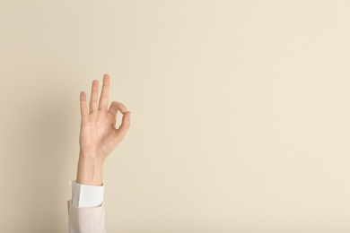 Photo of Young woman showing OK gesture on color background. Space for text