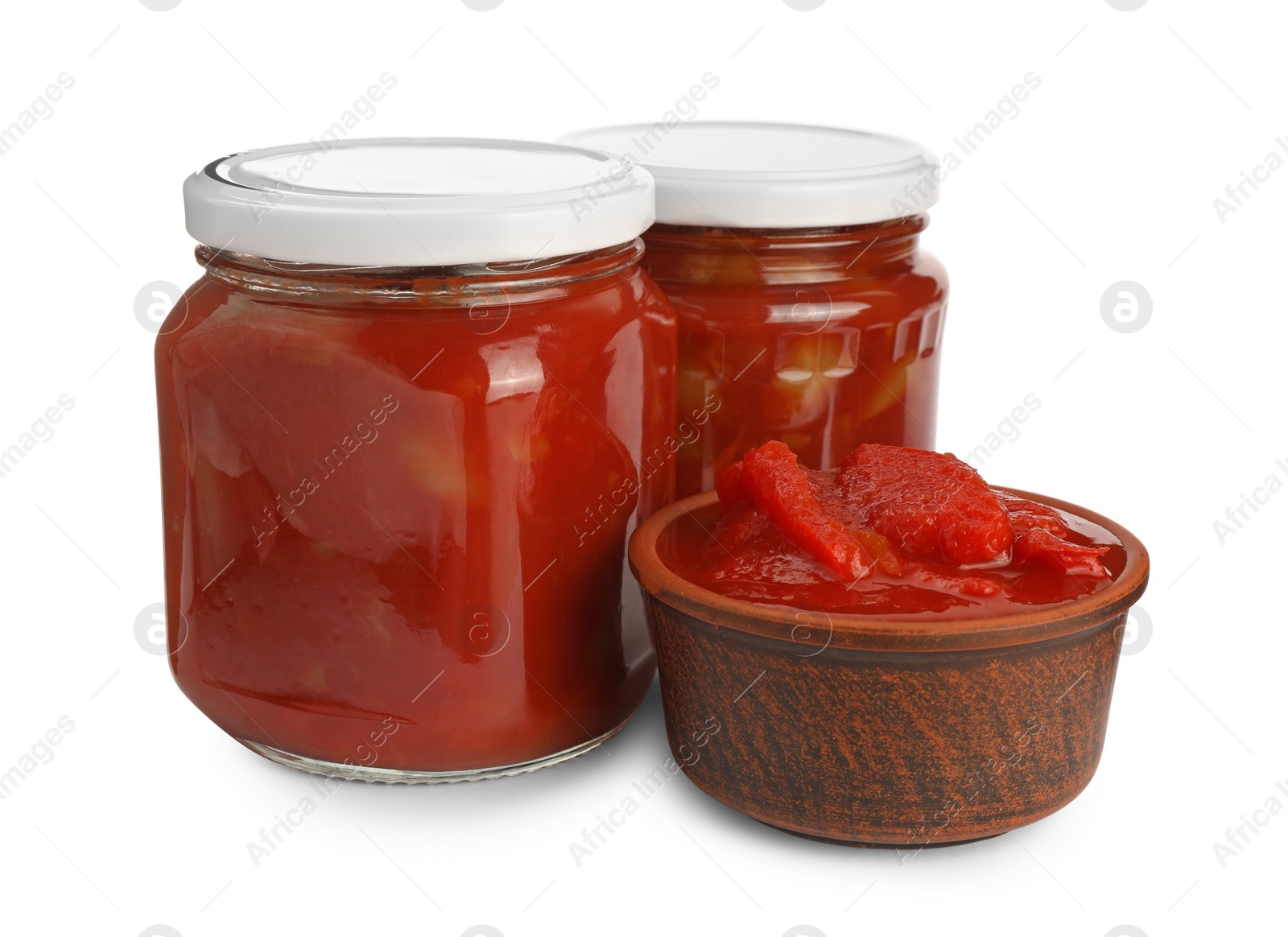 Photo of Glass jars and bowl of delicious lecho on white background