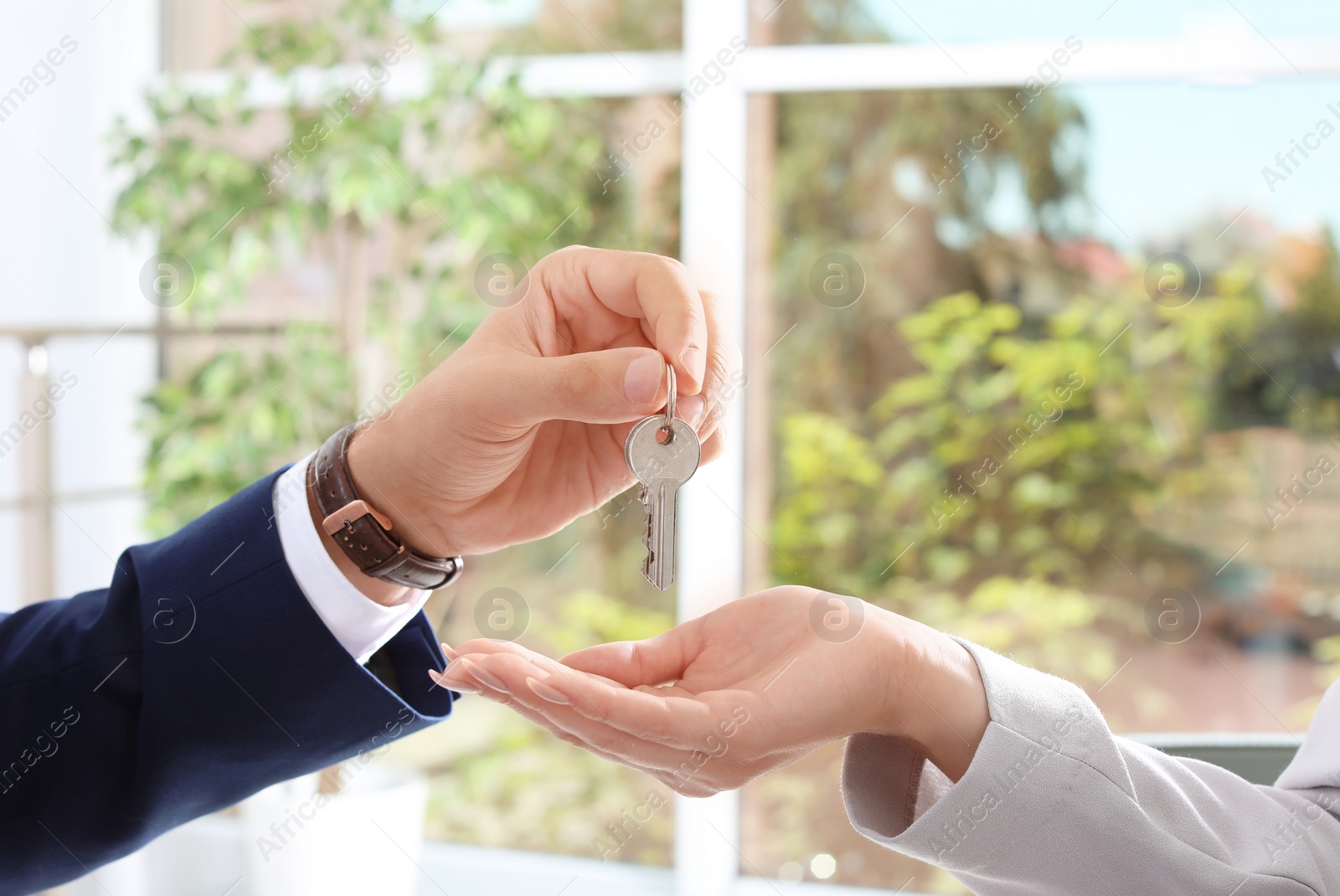 Photo of Real estate agent giving key to woman in office, closeup