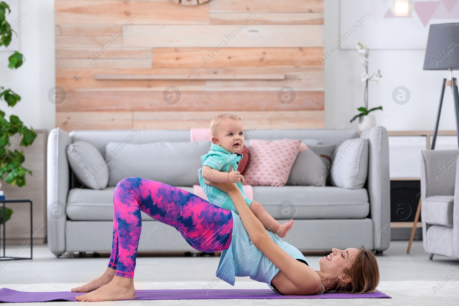 Photo of Young sportive woman doing exercise with her son at home. Fitness training