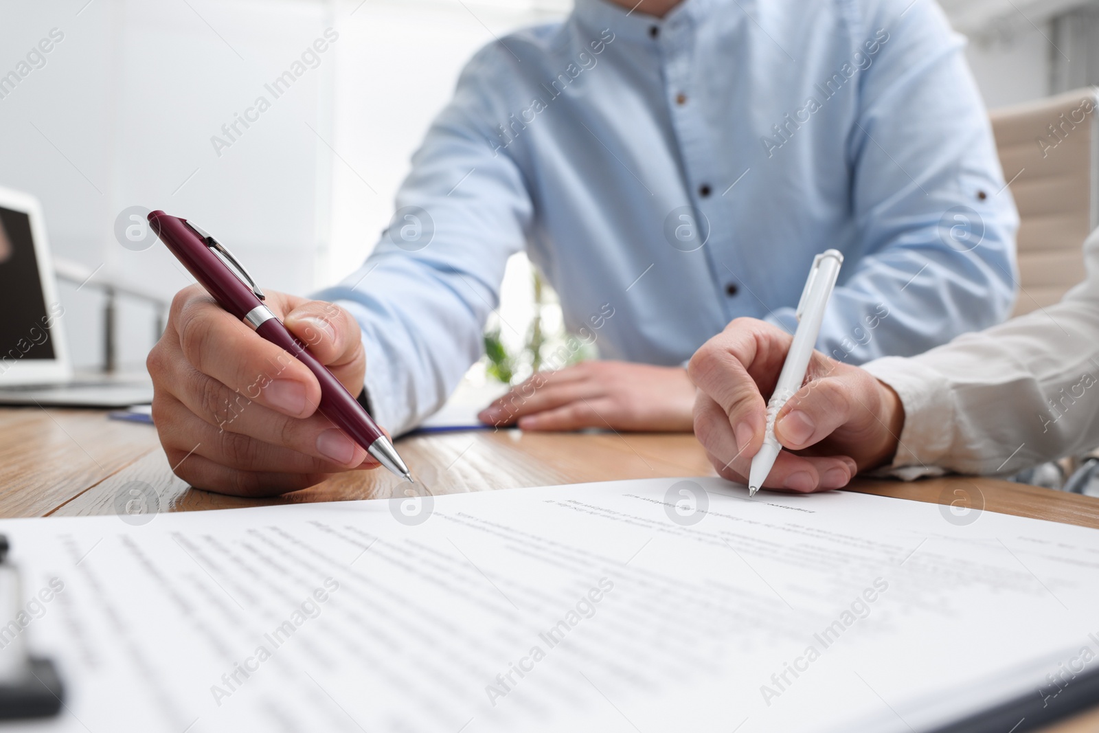 Photo of Businesspeople signing contract at table in office, closeup