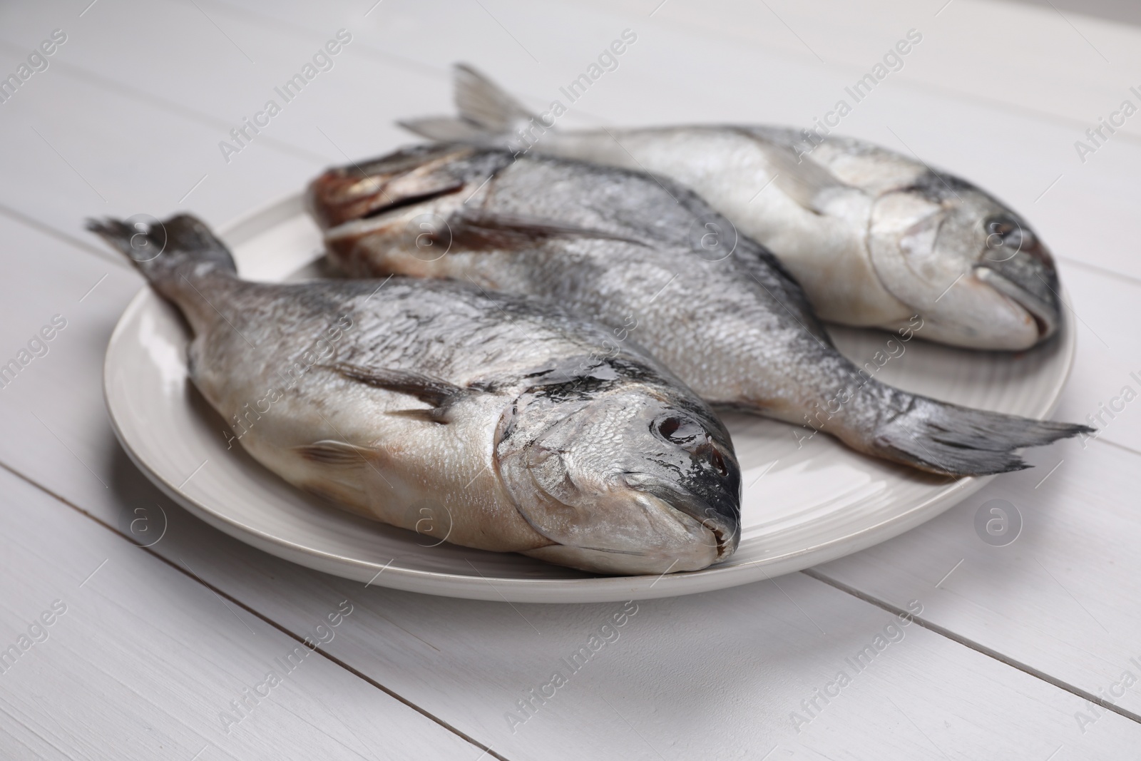 Photo of Fresh raw dorado fish on white wooden table, closeup