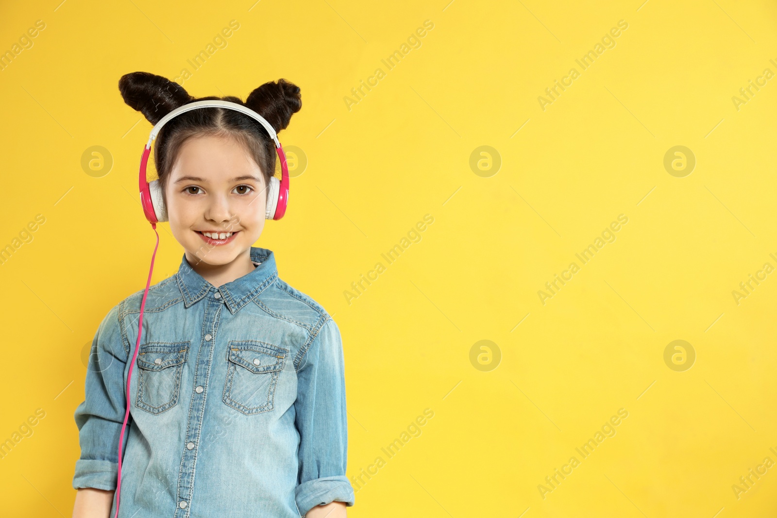 Photo of Cute girl enjoying music in headphones on color background. Space for text