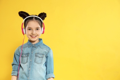 Cute girl enjoying music in headphones on color background. Space for text