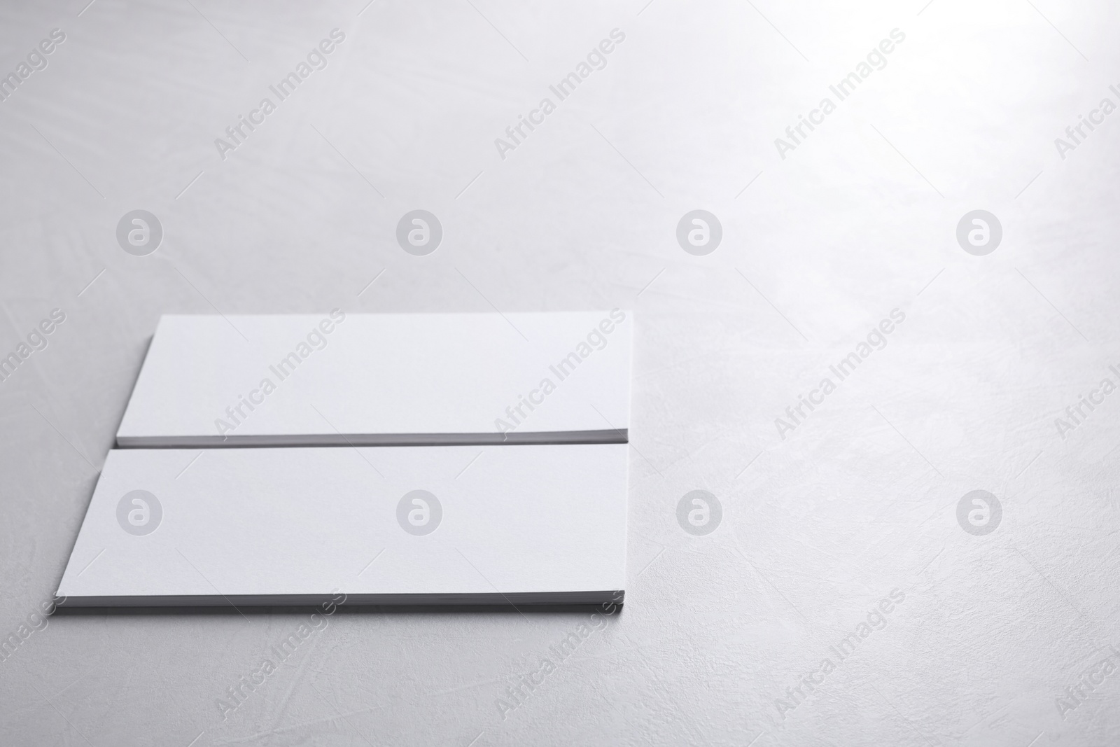 Photo of Blank business cards on light grey textured table, closeup. Mockup for design