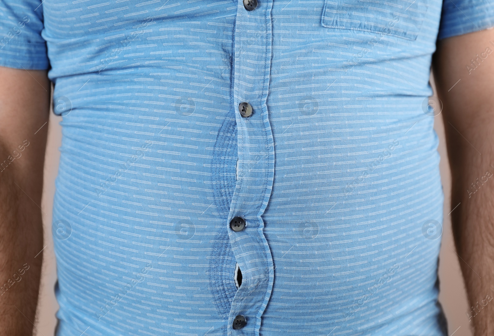 Photo of Overweight man with large belly in tight shirt , closeup