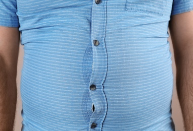 Photo of Overweight man with large belly in tight shirt , closeup