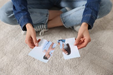 Photo of Woman holding torn photo on floor, closeup. Divorce concept