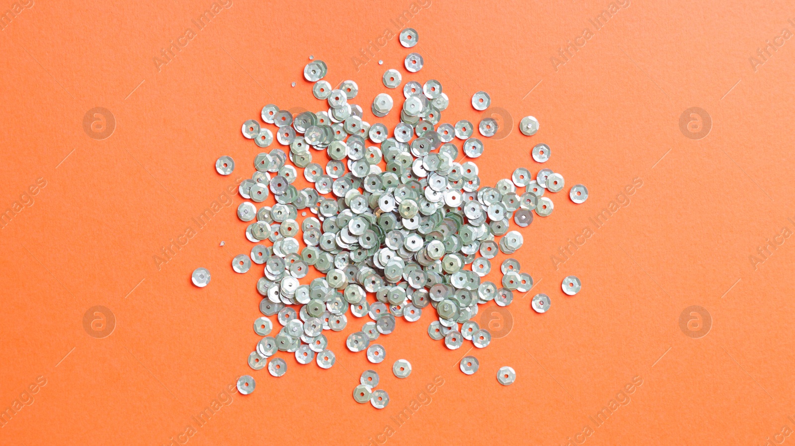 Photo of Pile of beautiful sequins on orange background, flat lay