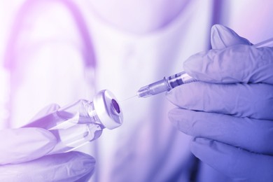 Image of Doctor filling syringe with medication from vial, toned in purple