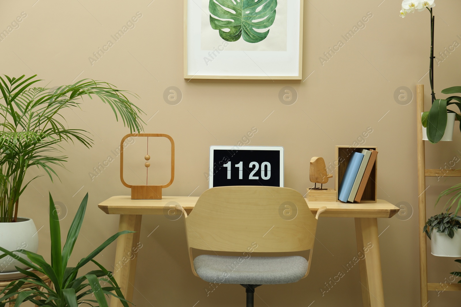 Photo of Stylish workplace with laptop, armchair and houseplants in room. Interior design
