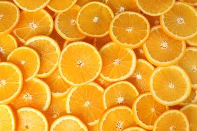 Photo of Many sliced fresh ripe oranges as background, top view