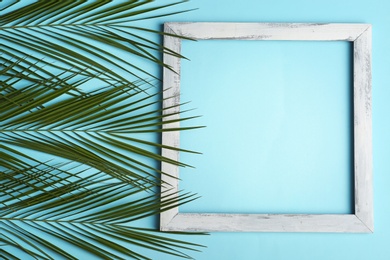 Photo of Square frame and tropical leaves on color background, top view