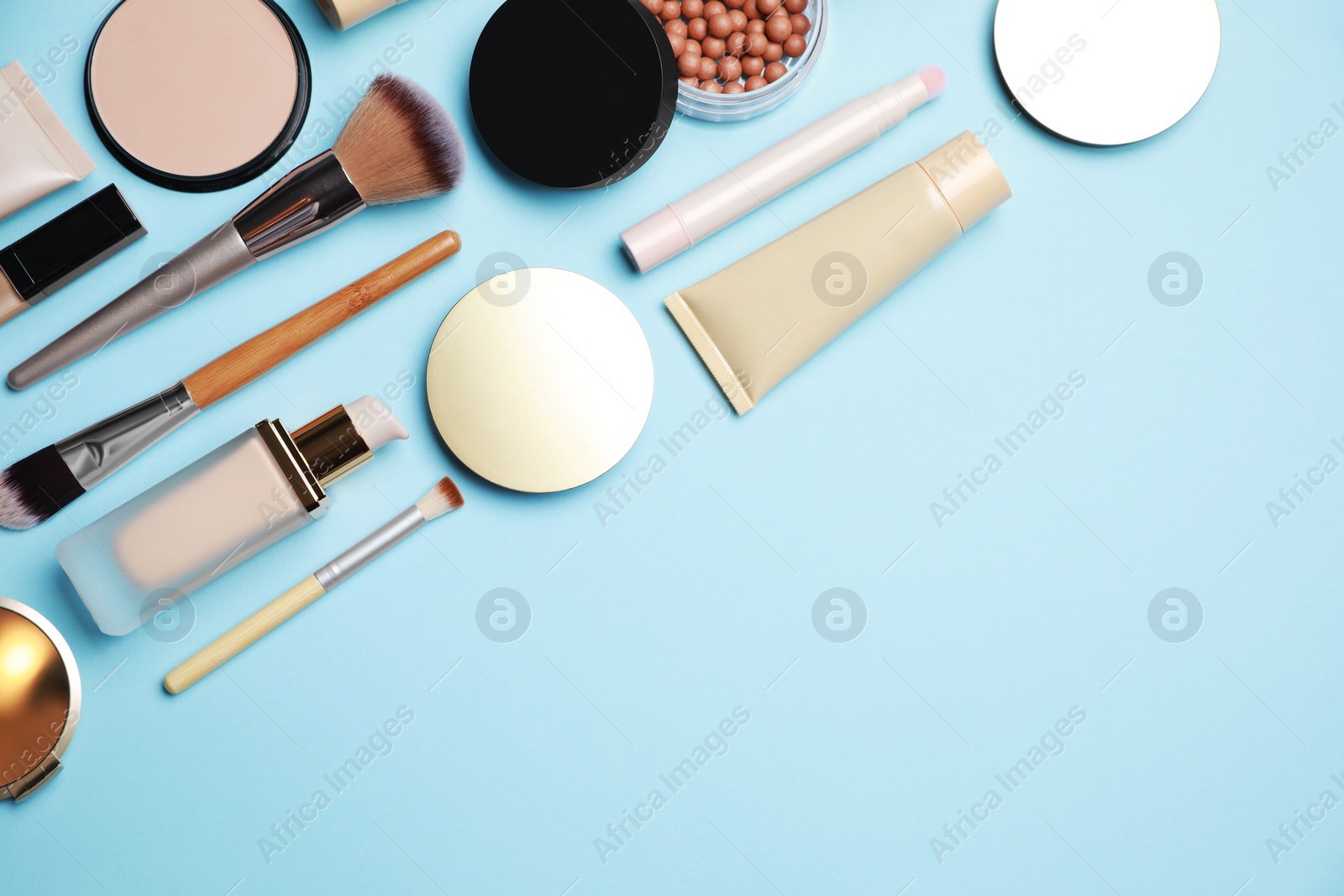 Photo of Face powders and other decorative cosmetic products on light blue background, flat lay. Space for text