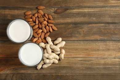 Glasses with almond and peanut milk on wooden background