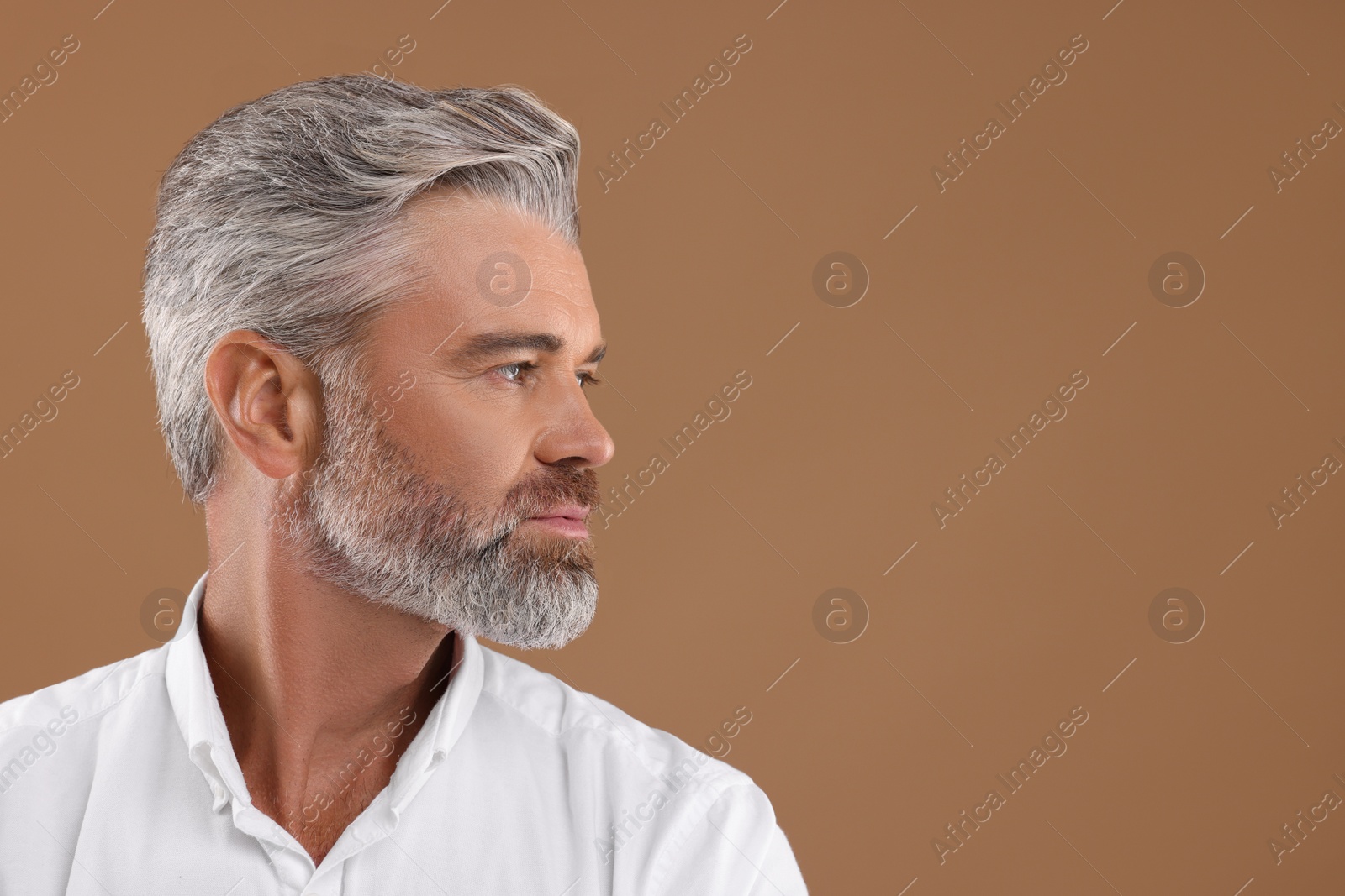 Photo of Portrait of confident man with beautiful hairstyle on light brown background. Space for text