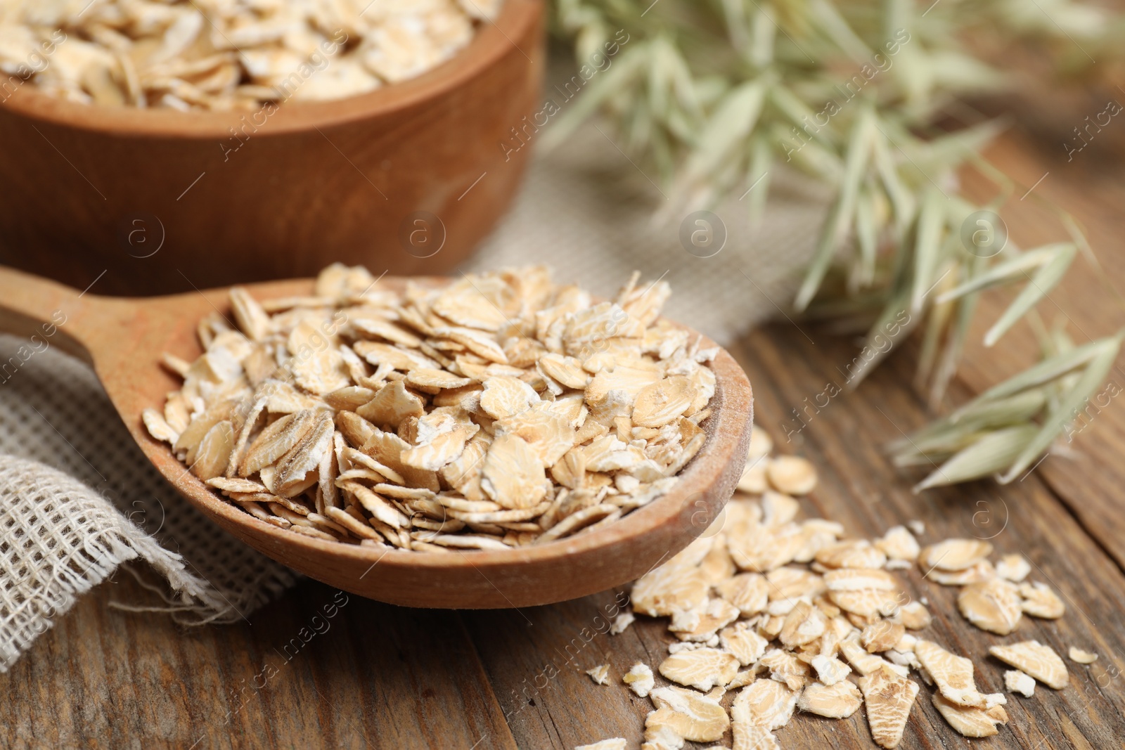 Photo of Spoon with oatmeal and florets on wooden table, closeup