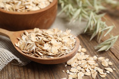 Photo of Spoon with oatmeal and florets on wooden table, closeup