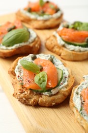 Photo of Tasty canapes with salmon, capers, cucumber and sauce on table, closeup