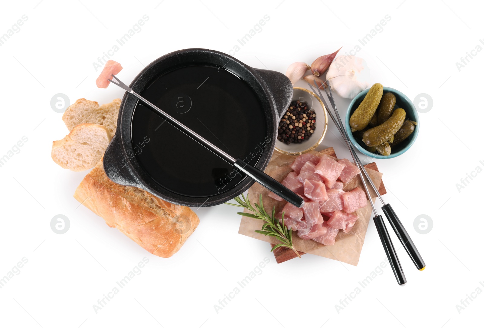 Photo of Fondue pot with oil, forks, raw meat pieces and other products isolated on white, top view