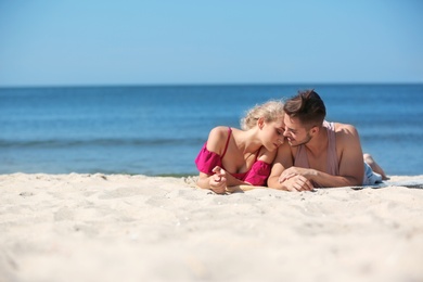 Photo of Happy young couple lying together at beach on sunny day