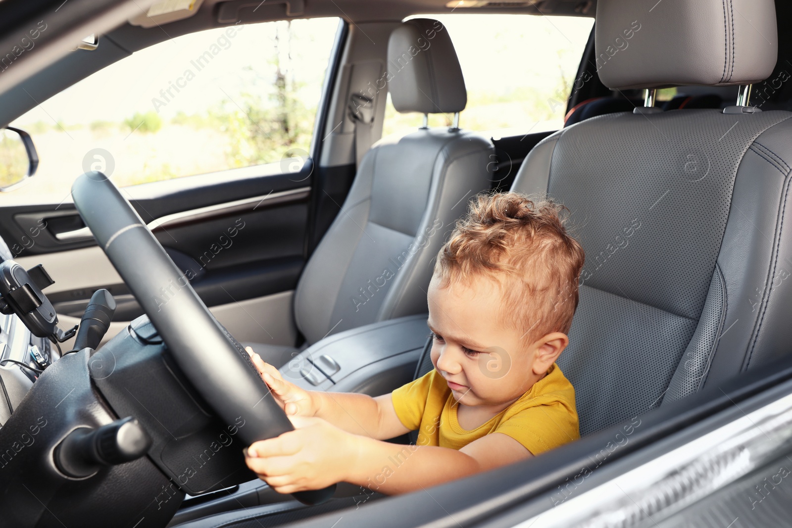 Photo of Little boy playing with steering wheel in car. Family trip