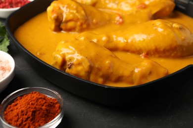 Tasty chicken curry and ingredients on black table, closeup