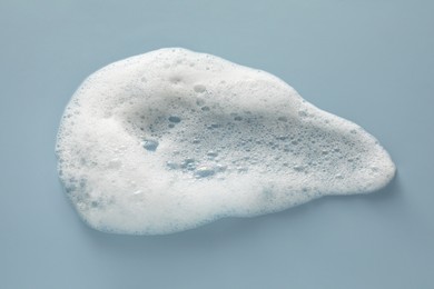 Photo of Smudge of white washing foam on color background, top view