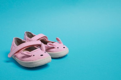 Cute baby shoes on light blue background, space for text