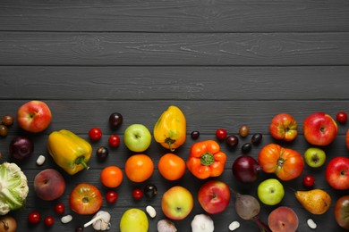 Different fresh vegetables and fruits on black wooden table, flat lay with space for text. Farmer harvesting