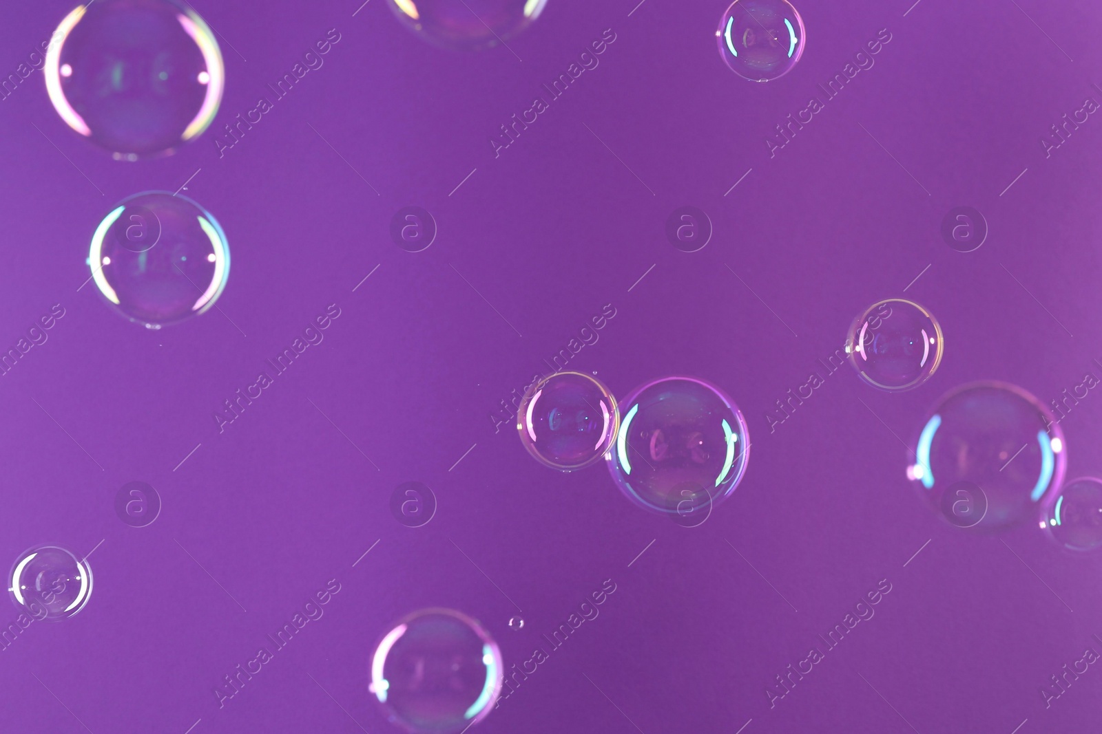 Photo of Beautiful transparent soap bubbles on violet background