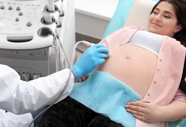 Photo of Young pregnant woman undergoing ultrasound scan in clinic