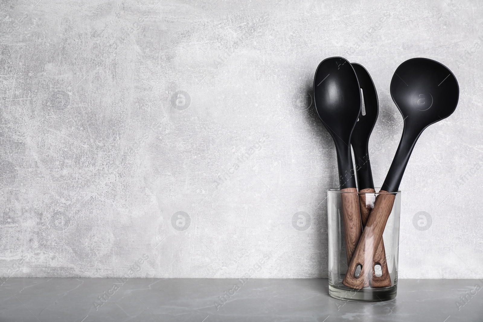 Photo of Holder with kitchen utensils on grey table. Space for text