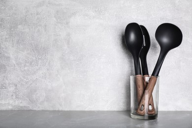 Photo of Holder with kitchen utensils on grey table. Space for text