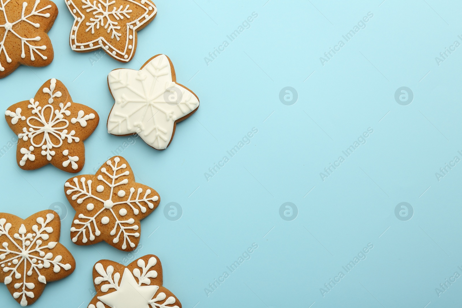 Photo of Tasty star shaped Christmas cookies with icing on light blue background, flat lay. Space for text