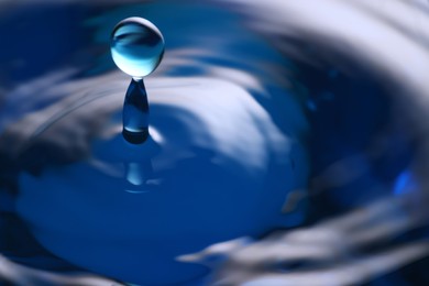 Splash of clear water with drop on blue background, closeup