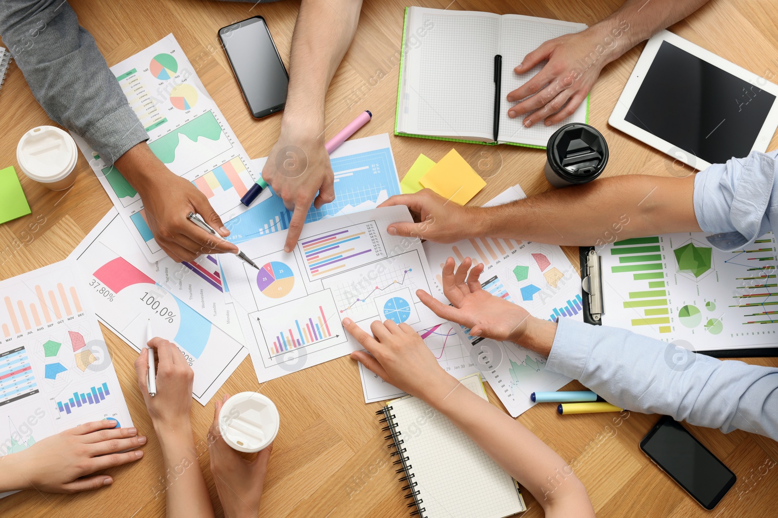 Photo of Team of employees working together at wooden table, top view. Startup project