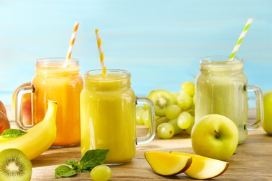 Photo of Mason jars of different tasty smoothies and fresh ingredients on wooden table