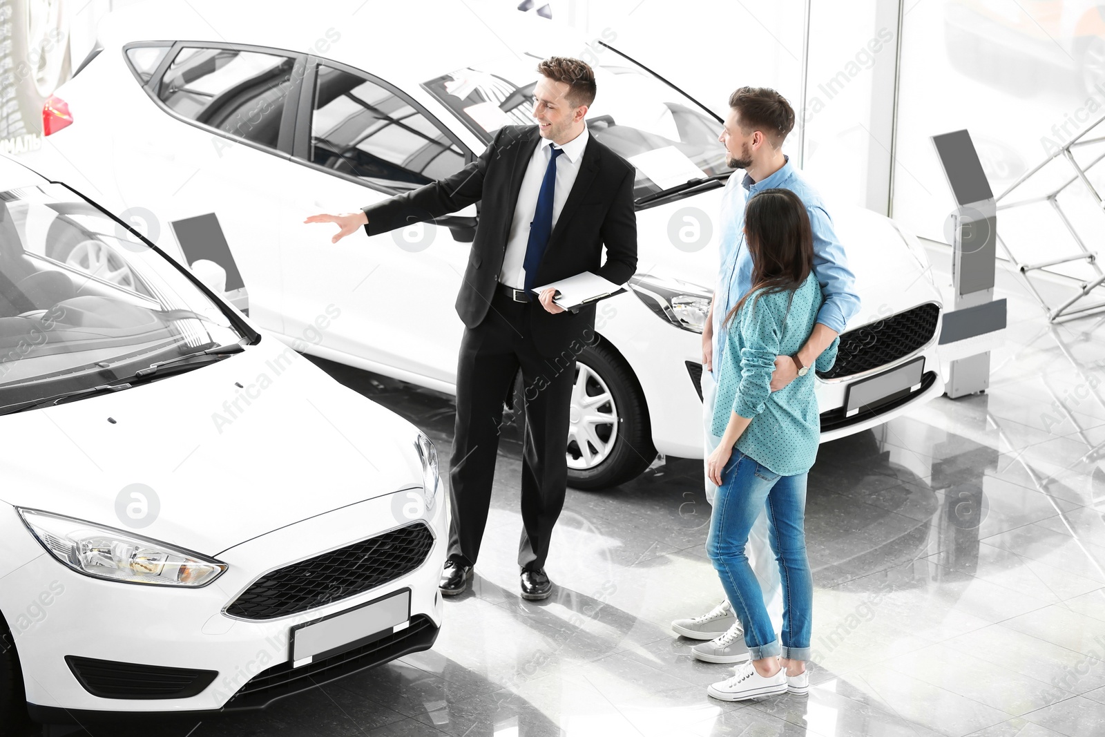 Photo of Young couple buying new car in salon