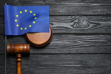 Photo of Judge's gavel and flag of European Union on black wooden table, flat lay. Space for text