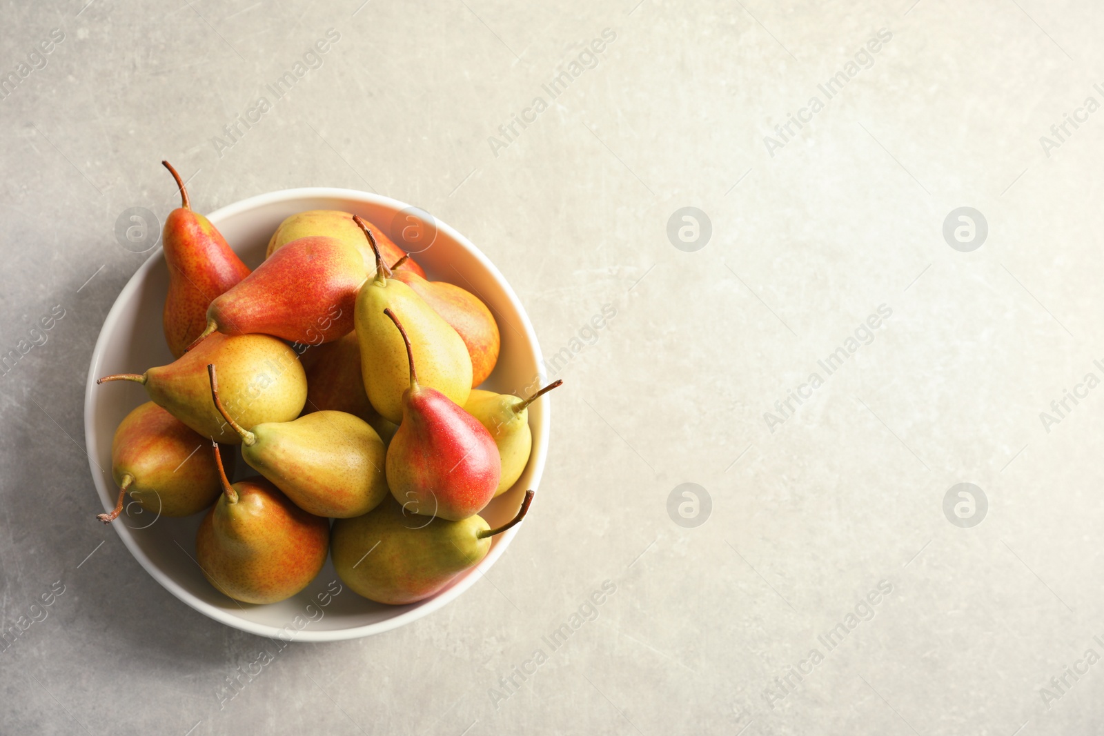 Photo of Plate with ripe pears on grey background, top view. Space for text