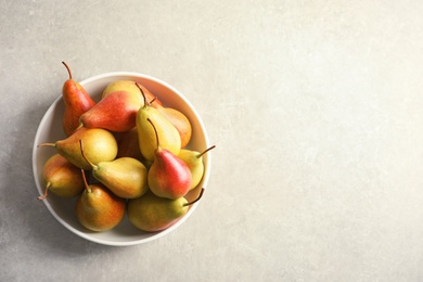 Plate with ripe pears on grey background, top view. Space for text