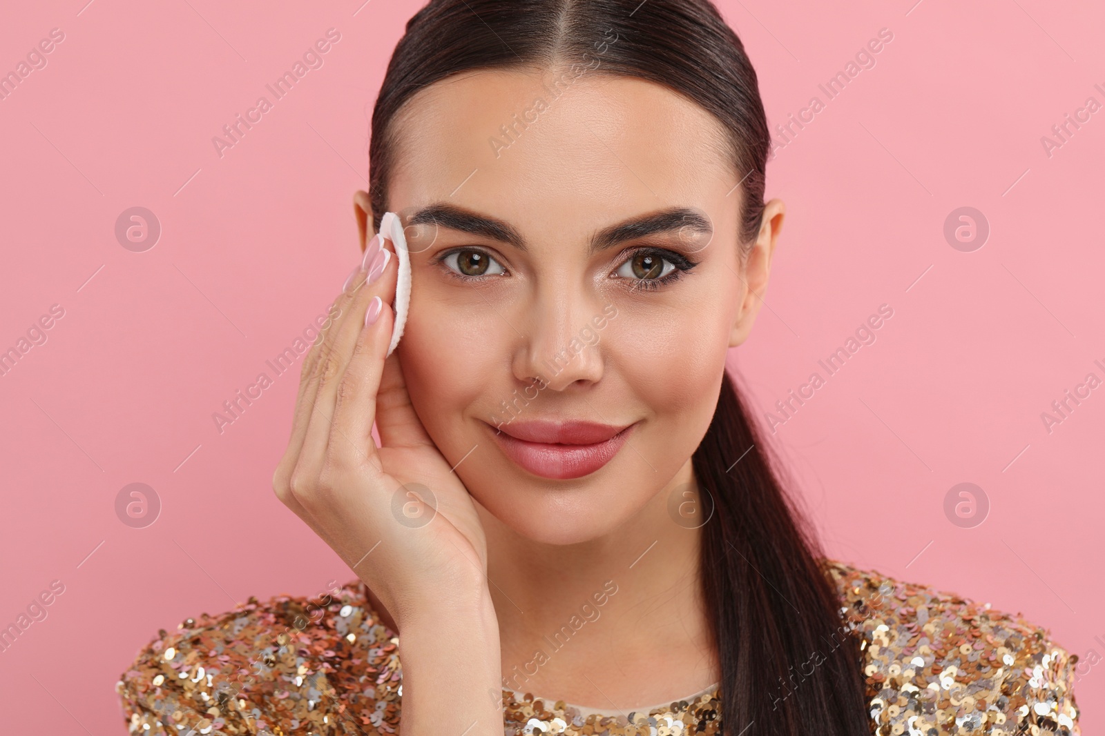 Photo of Beautiful woman removing makeup with cotton pad on pink background