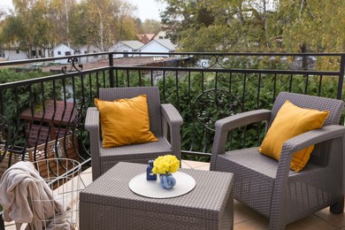 Orange pillows and yellow chrysanthemum flowers on rattan garden furniture outdoors