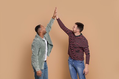 Photo of Men giving high five on beige background