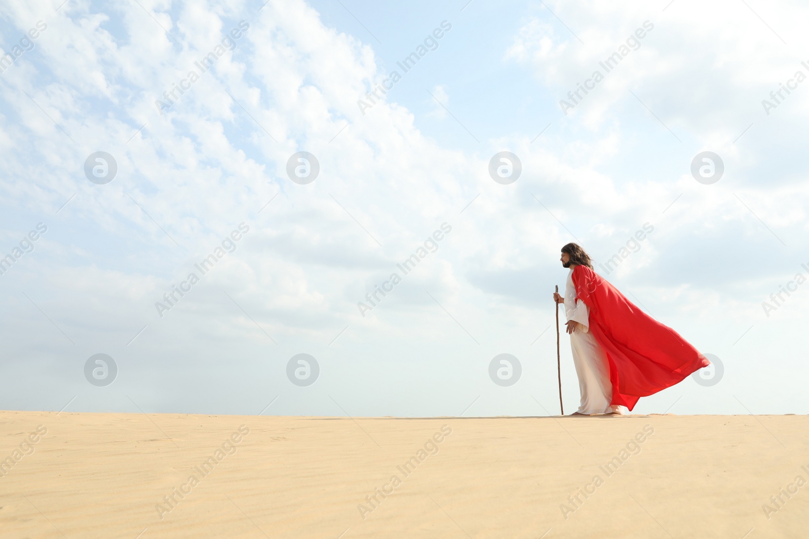 Photo of Jesus Christ walking with stick in desert. Space for text