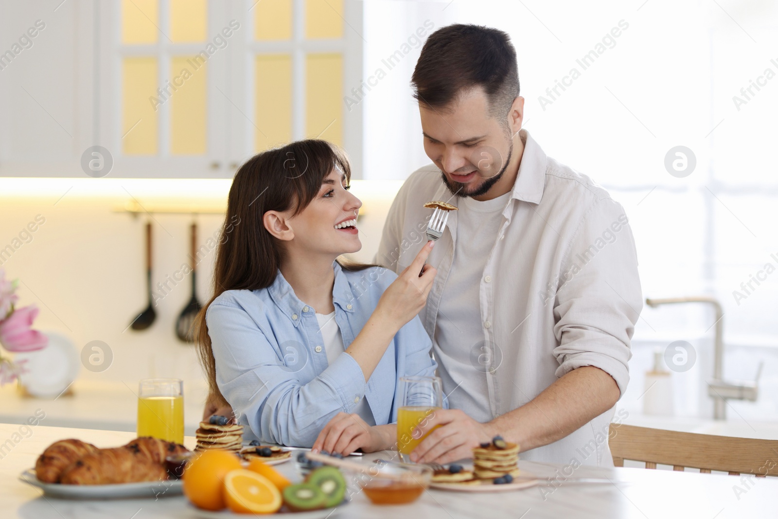 Photo of Tasty breakfast. Happy wife feeding her husband at home