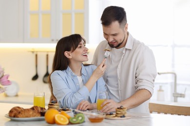 Tasty breakfast. Happy wife feeding her husband at home