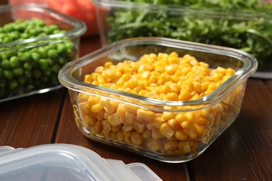Containers with corn and fresh products on wooden table, closeup. Food storage